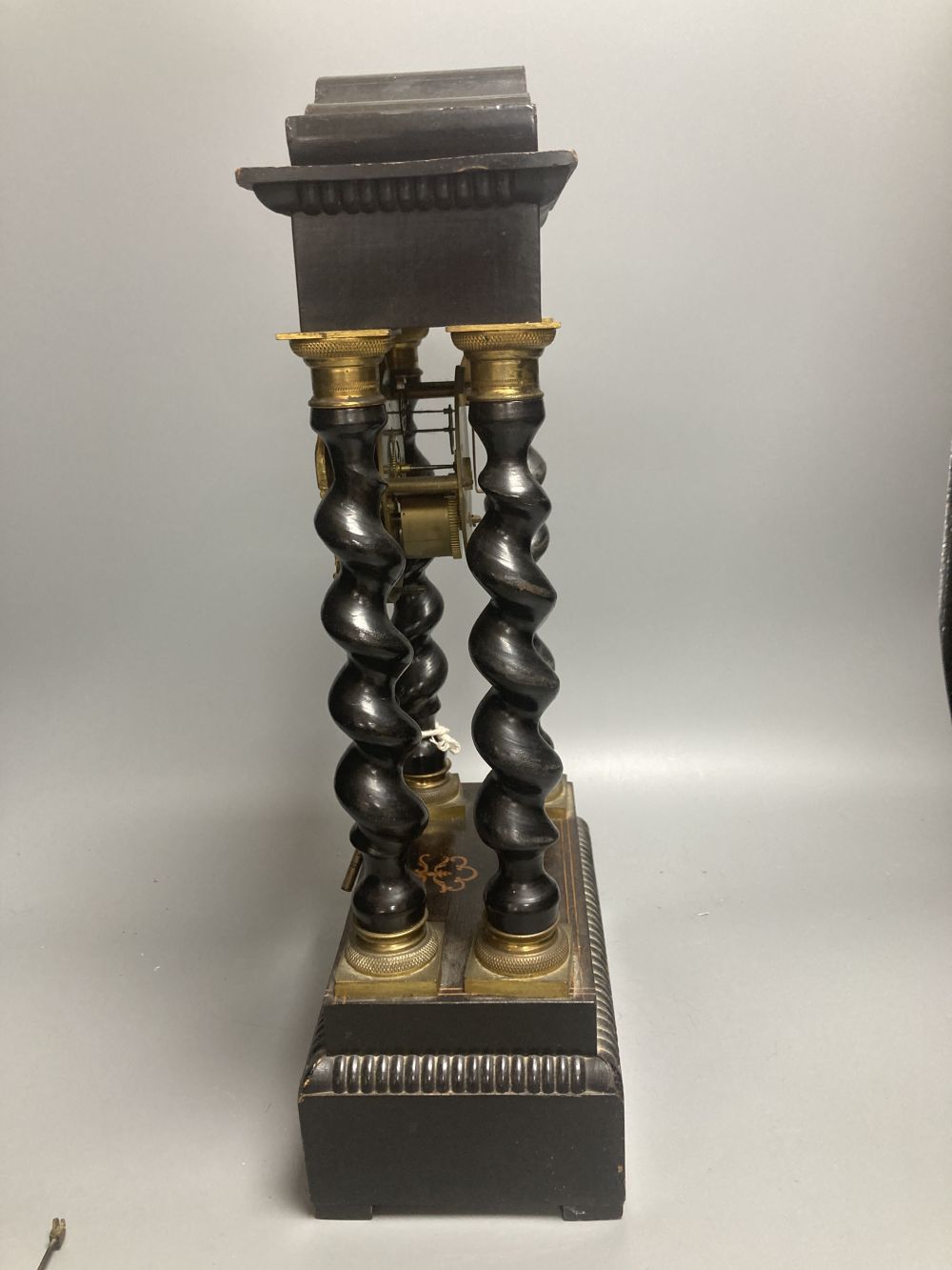 A 19th century French portico ebonised mantel clock, enamelled dial and timepiece movement, gridiron pendulum, 44cm high